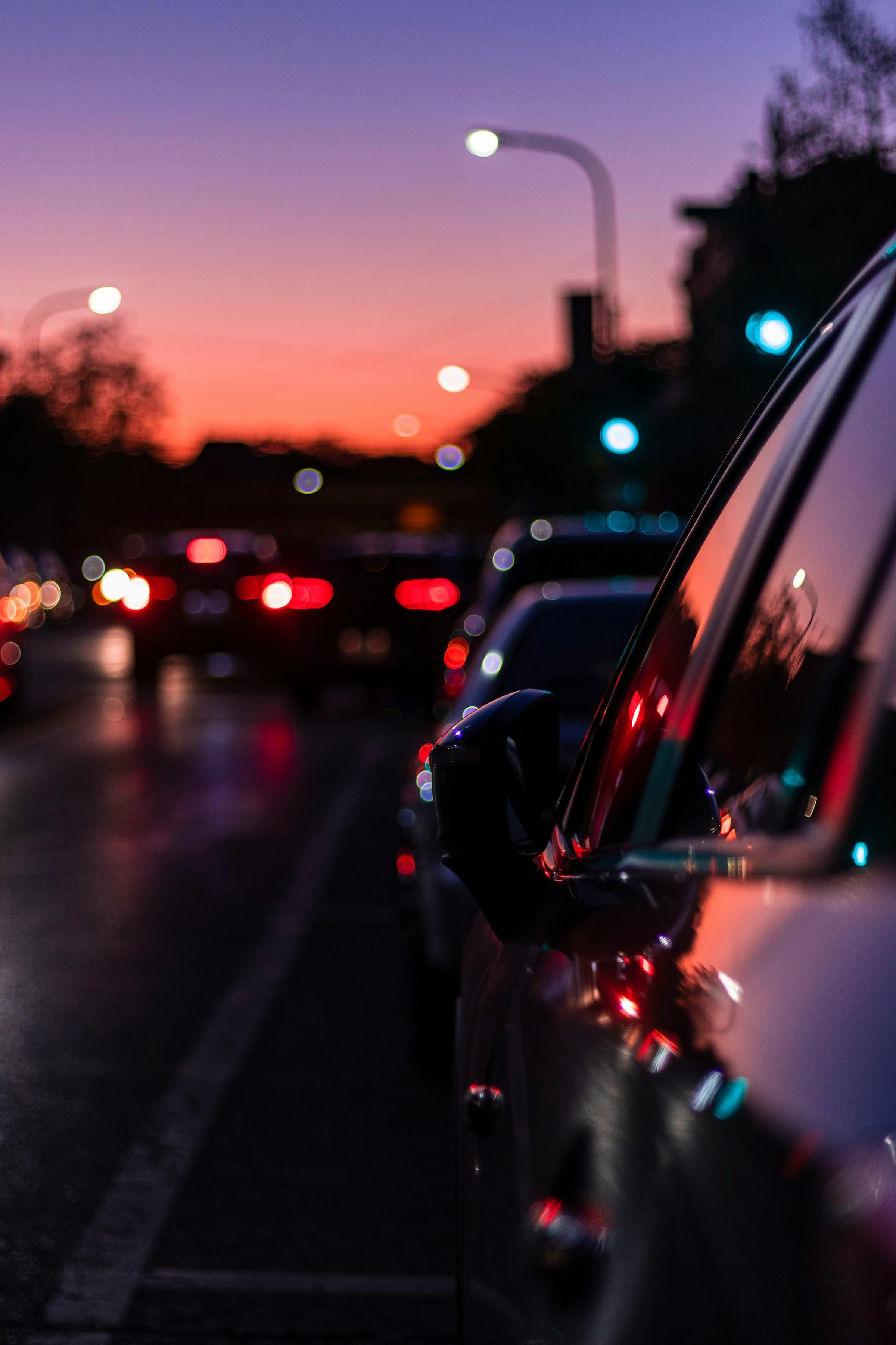 Company traffic queuing at dusk, brake lights along a wet road