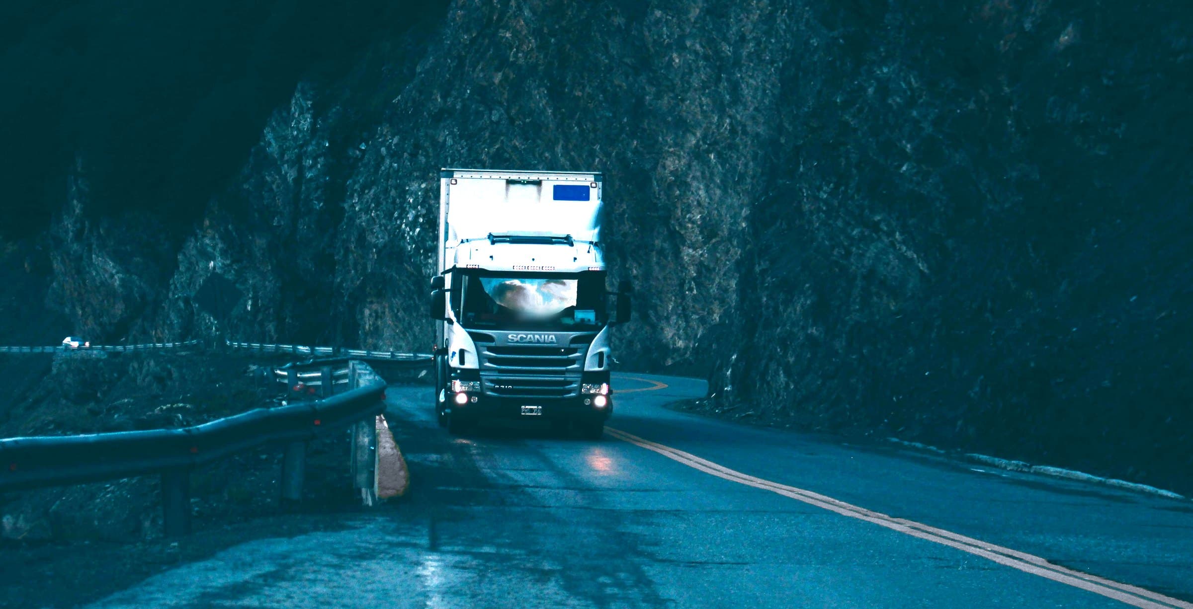 A commercial vehicle on a wet road at dusk