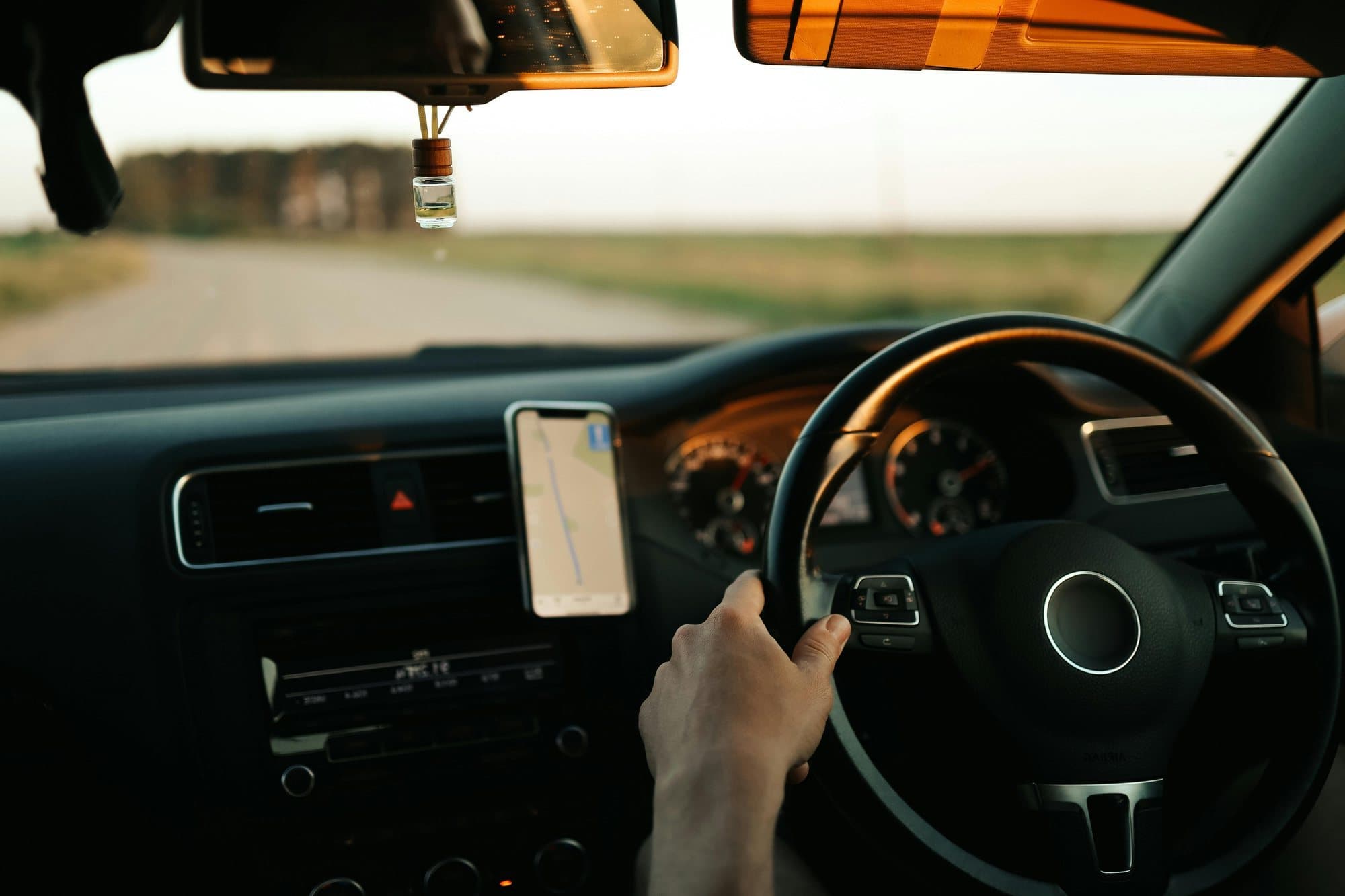 The view from the passenger seat on an open road, hands on the wheel